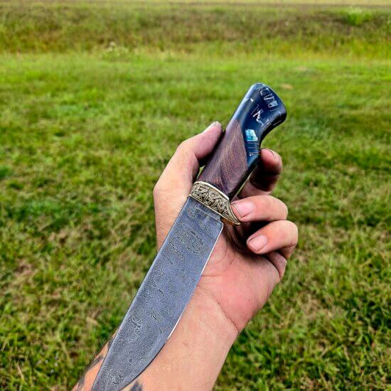 He who wears the Helm of Awe shall have no fear..." ⚔️ Introducing the Aegishjalmur Hunter. Hand-forged from 220-layer ladder Damascus and featuring a custom bronze Celtic guard. The handle captures the "smokey blue" of Fafnir’s lair, created by @MidknightArts. Despite the heavy steel and bronze, this blade feels weightless and fast in the hand. We finished it by setting the Helm of Awe symbol directly into the pommel—ancient protection for modern use.